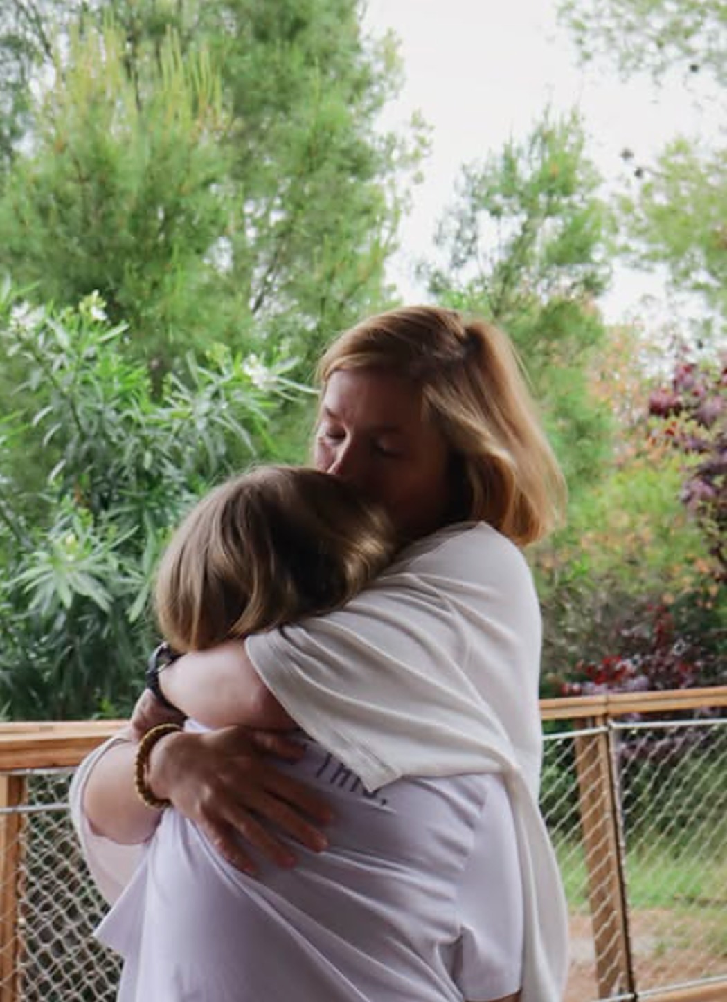 Abrazo entre madre e hija al final de la clase, con el pinar de fondo
